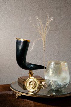 a glass vase sitting on top of a table next to a gold plated object