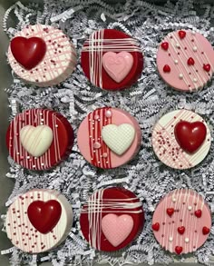 twelve heart shaped cookies in a box with red and white icing on them, all decorated like hearts