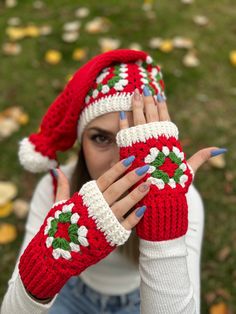 a woman wearing red and white knitted mittens holding her hands in front of her face