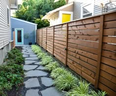 a small backyard with stone walkway and wood fenced in area next to the house