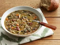 a white bowl filled with soup next to a loaf of bread on top of a wooden table