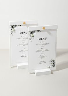 two white menus sitting on top of each other in front of a white wall