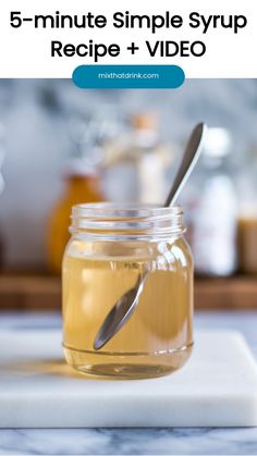 a jar filled with honey sitting on top of a white counter next to a spoon