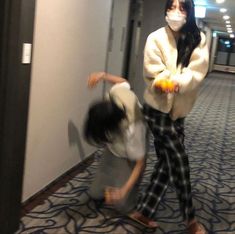 two people wearing masks are dancing in an office building hallway while another person is on the floor