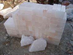 several pieces of white rock sitting on top of a dirt ground next to a pile of rocks