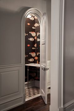 an arched doorway leads to a bathroom with fish on the wall and checkered floor