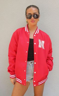 Looking for the ultaimte gameday outfit? Look no further than this vintage inspired varisty jacket. This Nebraska red snap front jacket has the "N" logo on the front and "Huskers" on the back. 


Mary Claire is 5’9” and is wearing size medium

medium measurements: 47” bust | 29” length

100% polyester


WE ONLY OFFER STORE CREDIT FOR RETURNS! Feel free to email us at orders@shopriffraff.com or DM us with any questions regarding fit, styling, or our return policy in general. University Red Varsity Jacket For Fall Streetwear, Red Varsity Jacket With Baseball Collar For Fall, Red Sporty Varsity Jacket For Fall, Sporty Red Varsity Jacket For Fall, Casual Long Sleeve Varsity Jacket For Fans, Red Collegiate Varsity Jacket For Fall, University Red Varsity Jacket For College, University Red Varsity Outerwear For College, Casual Game Day Outerwear With Letter Print