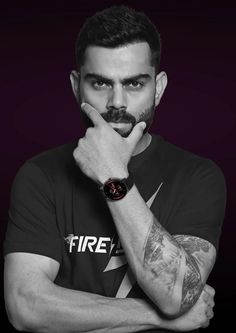 a man with tattoos and a watch on his wrist is posing for a photo in black and white