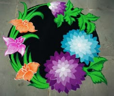 a black rug with colorful flowers painted on the top and bottom is shown in front of a tile floor