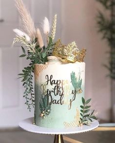 a birthday cake decorated with greenery and gold