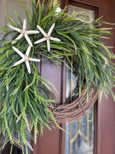 a wreath with white starfishs hanging from it's side on a door