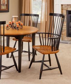 a dining room table with four chairs and a fireplace in the backgrounge