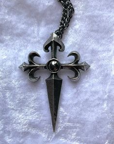 The charge of the 12th century Spanish knights, The Order of St. James of the Sword, vowed to protect pilgrims and extirpate infidels. An antiqued pewter cross pendant in a traditional style, raised in relief with fleur-de-lys ends to the arms of the cross and a sword-pointed shaft, and a dark, round hematite cabochon at its centre. The pendant comes with a velvet gift pouch. Made by Kiss of a red rose with help from Alchemy England 1977. Metal Casting Jewelry, Skull Necklaces, Silver Jewelry Aesthetic, Stack Jewelry, Jewelry Grunge, Wedding Jewelry Silver, Ethereal Jewelry, Jewelry Stack, Dope Jewelry Accessories