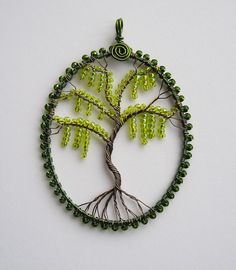 a wire tree with green beads hanging from it's sides on a white surface