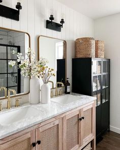 a bathroom with two sinks, mirrors and vases on the counter top in front of it