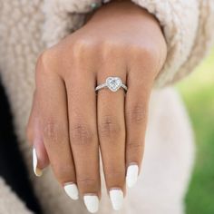 a woman's hand with a diamond ring on her finger and manicured nails