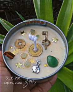 a hand holding a cup filled with coins and charms