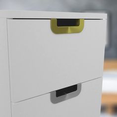 a close up of a white drawer with yellow handles