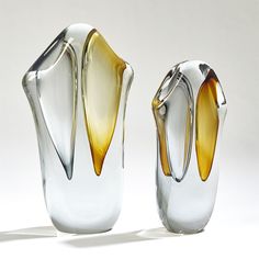 two glass vases sitting next to each other on a white surface with shadows from them