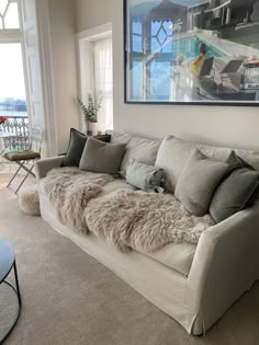 a living room filled with furniture and a large painting on the wall above it's windows