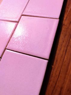 a close up view of pink tiles on a wooden floor