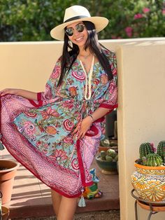 The Bora Bora Botanical Midi Kaftan radiates a refreshing charm with its beautiful blue floral design, complemented by a vibrant red and pink border. This exquisite kaftan features intricate botanical prints that showcase exceptional craftsmanship, blending elegance with a bold splash of color. The flowing silhouette and striking details make it a standout piece, perfect for adding a touch of vibrant sophistication to your wardrobe. 100% cotton voile Length 39" One size fits all with adjustable Traditional Pink Floral Print Kaftan, Traditional Pink Kaftan With Floral Print, Red V-neck Kaftan With Vibrant Print, Traditional Red Kimono For Vacation, Traditional Floral Print Spring Kaftan, Traditional Spring Floral Print Kaftan, Traditional Floral Print Kaftan For Spring, Traditional Spring Floral Kaftan, Multicolor Floral Print Kaftan For Festival