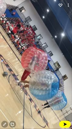 two inflatable balls are on the court as people watch from the sidelines