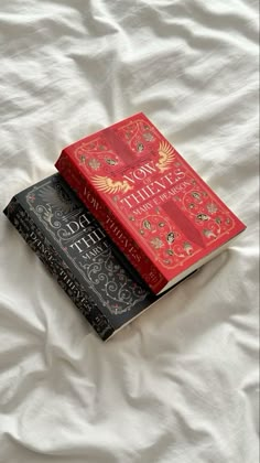 three books sitting on top of a bed next to each other in front of a white sheet