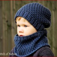 a young boy wearing a blue knitted hat and scarf with a hood on his head