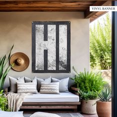 a living room filled with lots of furniture next to potted plants and a hat hanging on the wall