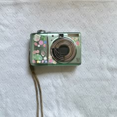 an old camera is laying on a white sheet with flowers and hearts all over it