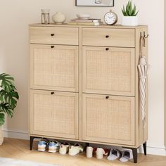 a wooden cabinet with several pairs of shoes on it and a plant in the corner