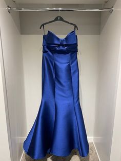 a blue dress hanging on a hanger in a closet