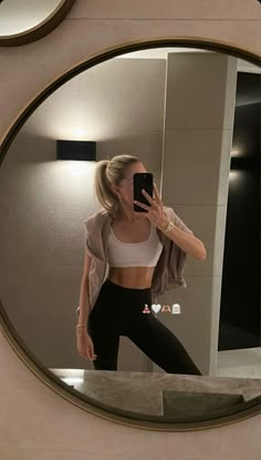 a woman taking a selfie in front of a mirror while wearing leggings