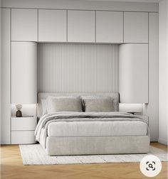 a white bedroom with a bed, nightstands and lamps on the side of it