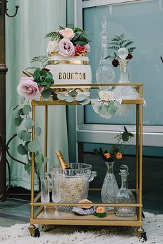 a gold bar cart with flowers and bottles on it