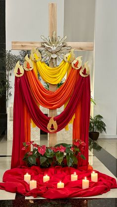 an altar decorated with red, orange and yellow drapes next to candles on the floor