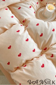 the comforter has hearts on it and is next to a glass of orange juice