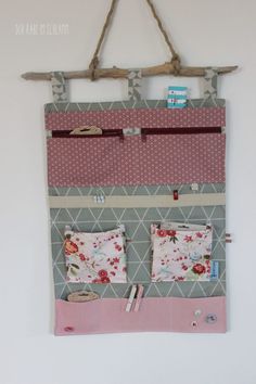 a wall hanging organizer made out of fabric and wood sticks with two pockets on each side