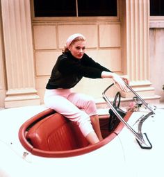 a woman sitting on top of a red car