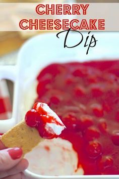 cherry cheesecake dip in a white dish with a cracker being dipped into it