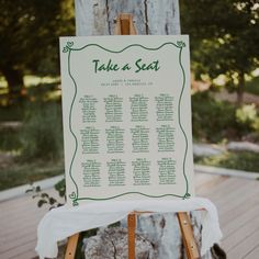 a wooden easer with a seating chart on it sitting in front of a tree