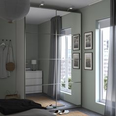 a bedroom with a large mirror on the wall next to a bed and dresser in front of two windows