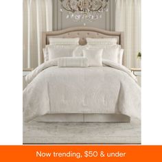 a white bed in a bedroom with chandelier above it and the words now trending, $ 50 & under