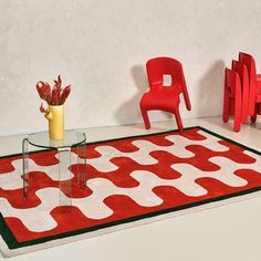 a red chair sitting next to a table on top of a rug