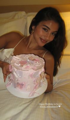 a woman laying in bed with a cake