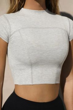 Fitted crop tee with cap sleeves, stitch detailing, and a mini mock neckline. Feel a subtle pop of texture in this tight-knit ribbed fabric. It's stretchy, comfortable, and forms perfectly to your body. Color: Pearl Grey Rib Sizing: X/S (0-2), S/M (4-6), M/L (8-10) Model is 5'8" and is wearing size X/S Fabric: 95% Ribbed Rayon, 5% Spandex Care: Machine wash cold with like colors. Lay flat to dry. Knit Fabric Tops, Fitted Clothes, Fitted Crop Top, Form Fitting Tops, Ribbed Shirt, Rib Top, Textured Top, Joah Brown, Cap Fashion