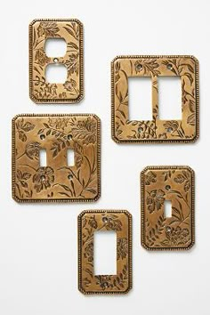 four decorative switch plates with flowers and vines on the front, one has a light switch plate