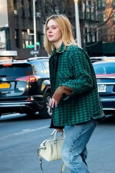 a woman is walking down the street with her hand in her pocket and holding a purse