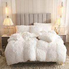 a bed with white fluffy blankets and pillows